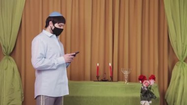 Chuppah töreninden önce, bir sinagog salonunda koruyucu maskeli bir Yahudi damat telefonla SMS çevirir.