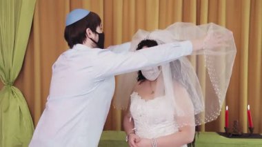 Çuppa töreni sırasında, sinagogda koruyucu maskeler takan bir Yahudi gelin ve damat gelinin yüzündeki örtüyü kaldırır.
