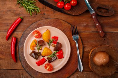 Tahta bir masada, taze sebzelerin yanında duran bir tabakta antimakarna. Yatay fotoğraf