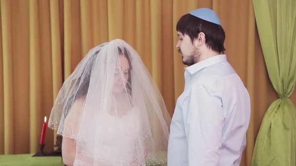 During the chuppah ceremony, the Jewish bride and groom in the synagogue lifts the veil from the brides face — Stock Video