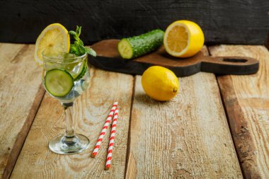 Limonlu salatalık suyu ve nane şekeri. Limon ve salatalık yakınlarındaki siyah bir arka planda, tahta bir masada..