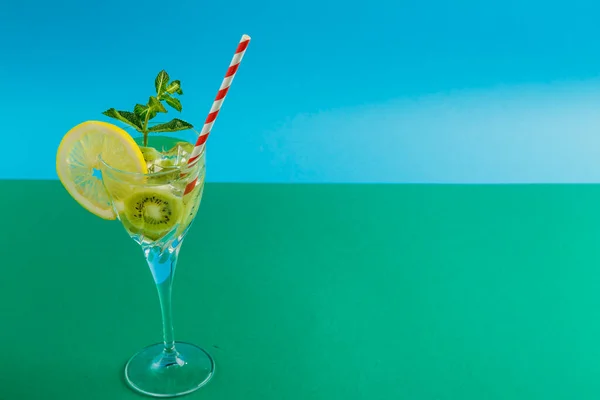 Ківі-коктейль, прикрашений лимоном і м'ятою в склянці на серветці на зеленому фоні . — стокове фото