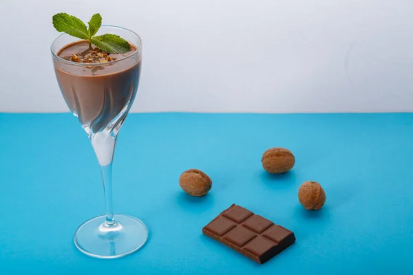 Fındık ve naneli çikolata kokteyli, fındık ve çikolatanın yanında mavi bir arka planda. Yatay fotoğraf