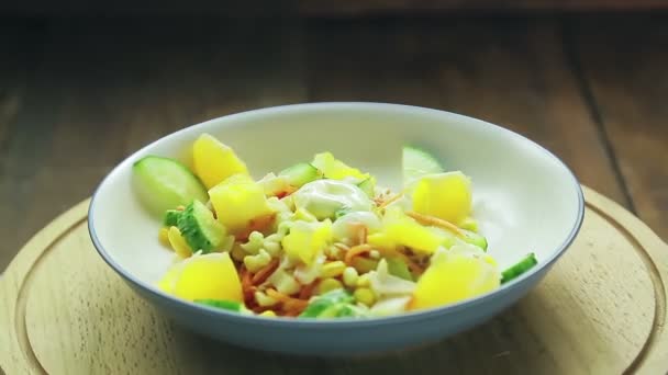 Sallad med krabbkött dekorerat med gurka och apelsin i en tallrik på ett trästativ roterar i en cirkel — Stockvideo