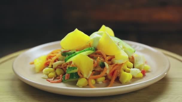 Salade met krab vlees versierd met komkommer en sinaasappel in een bord op een zwarte achtergrond draait in een cirkel. — Stockvideo