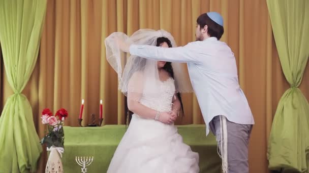 During the chuppah ceremony, the Jewish bride and groom in the synagogue lifts the veil from the brides face. — Stock Video