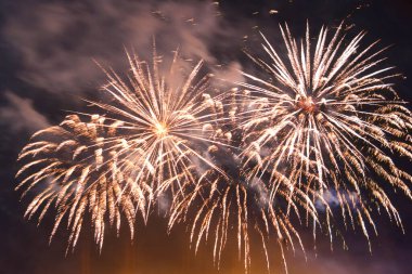 Dumanın içindeki karanlık gökyüzünde parlak havai fişekler. Yatay fotoğraf