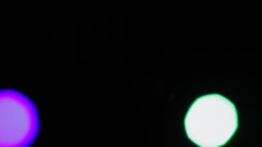 Renkli ışığın parlak LED ışınlarıyla siyah bir arkaplanda Bokeh bulanıklığı