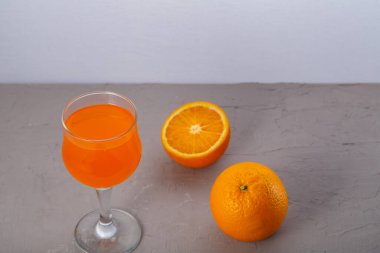 Portakalların yanında gri bir arka planda portakal suyu. Yatay fotoğraf