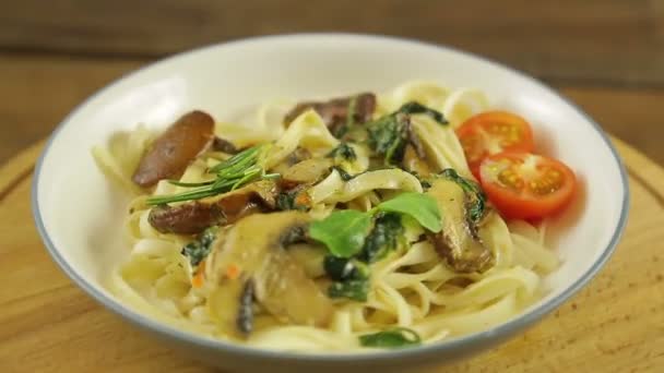 Udon con funghi e spinaci e pomodorini ciliegini in un piatto ruota in cerchio — Video Stock