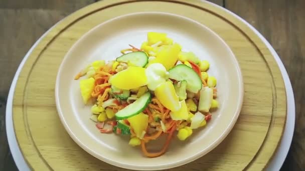 Ensalada de cangrejo decorada con pepino y naranja en un plato sobre un soporte de madera gira en círculo — Vídeos de Stock