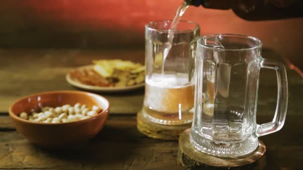 Espumante cerveja leve fria é derramada em canecas em uma mesa de madeira. — Vídeo de Stock