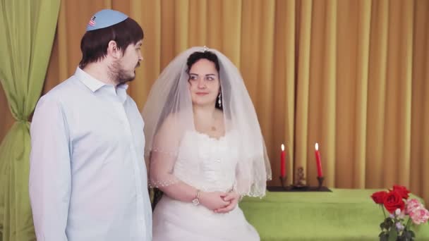 在圣餐仪式上，犹太新娘和新郎站在犹太会堂里，新郎和新娘相互凝视着对方 — 图库视频影像