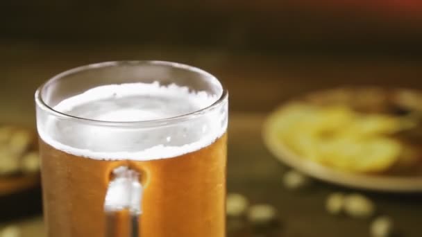 Im Hintergrund eines Imbisses dreht sich ein schäumendes kaltes, leichtes Bier in einem Glasbecher im Kreis — Stockvideo