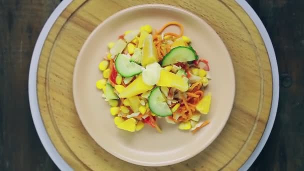 Insalata con carne di granchio decorata con cetriolo e arancia in un piatto su un supporto di legno ruota in un cerchio vista dall'alto. — Video Stock