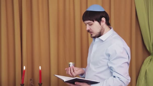 Before the chuppah ceremony, the Jewish groom reads prayers and psalms for siddur in the synagogue hall and makes kiddush for wine — Stock Video
