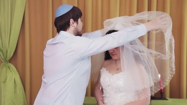 During the chuppah ceremony, the Jewish bride and groom in the synagogue lifts the veil from the brides face. — Stock Video
