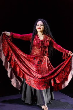 Uzun siyah saçlı çıplak ayaklı çingene kadın eteğini sallıyor. Dikey fotoğraf