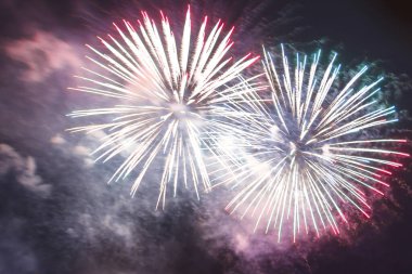 Dumanın içindeki karanlık gökyüzüne karşı parlak mor havai fişekler. Yatay fotoğraf