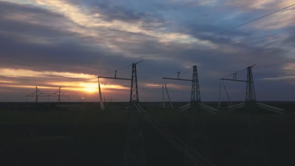 Wysokonapięciowe linie energetyczne o zmierzchu na tle zachodzącego słońca — Wideo stockowe