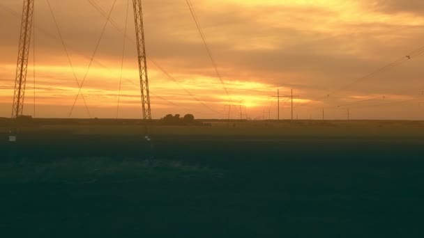 Wysokonapięciowe linie energetyczne na tle zachodzącego słońca na zwykłym aerovideo — Wideo stockowe