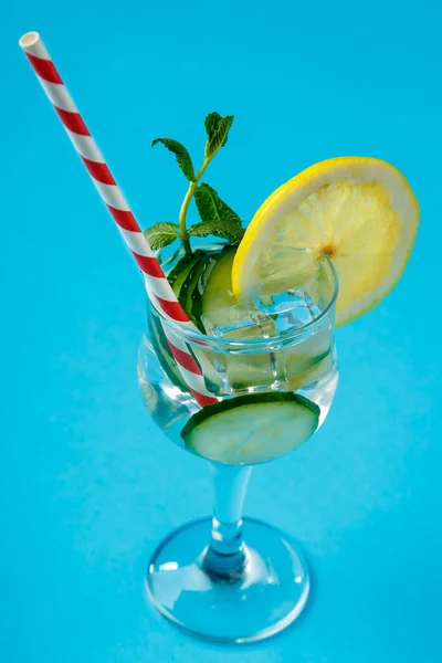 Коктейль з огірковою водою з лимоном та м'ятою у склянці на серветці на синьому фоні . — стокове фото