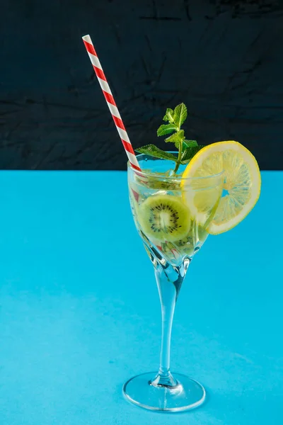 Ківі-коктейль, прикрашений лимоном і м'ятою в келиху на серветці на синьому фоні . — стокове фото