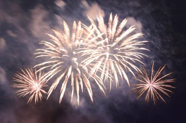 Dumanın içindeki karanlık gökyüzüne karşı parlak, ateşli havai fişekler..