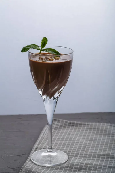 Chocolate cocktail with nuts and mint in a glass on a black background. — Stock Photo, Image