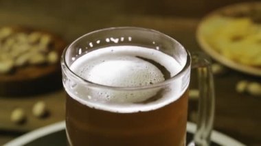 Cam bardakta köpüklü soğuk hafif bira ahşap bir masada daireler çizerek döner.