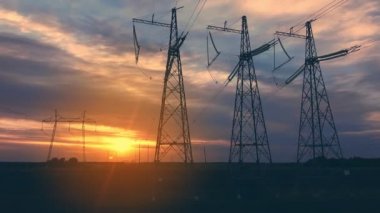 Yüksek voltajlı elektrik hatları gün batımında batımının arka planında