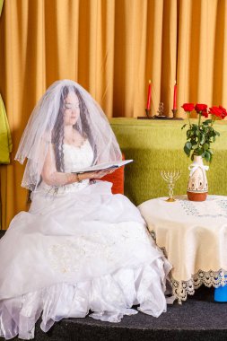 Beyaz elbiseli Yahudi gelin Chupa seremonisinden önce oturur ve Tethe okur. Dikey fotoğraf