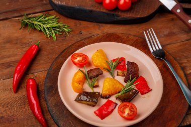 Tahta bir masada, taze sebzelerin yanında duran bir tabakta antimakarna. Yatay fotoğraf