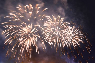 Dumanın içindeki karanlık gökyüzüne karşı parlayan havai fişekler. Yatay fotoğraf