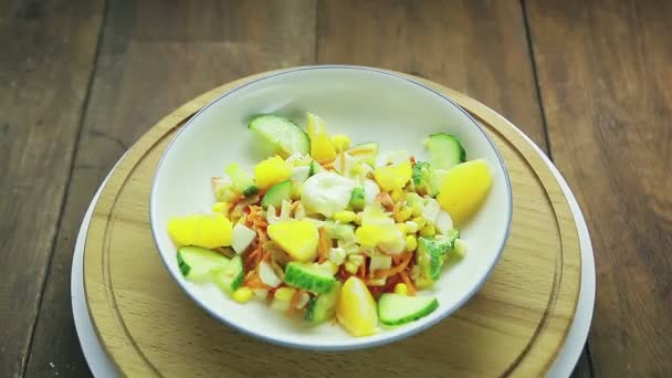 Salat mit Krabbenfleisch dekoriert mit Gurke und Orange in einem Teller auf einem Holzständer dreht sich im Kreis — Stockvideo