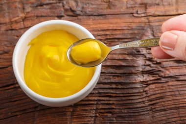 Peynir soslu sos tekneleri ve ahşap bir masada kaşıkta soslu eller..