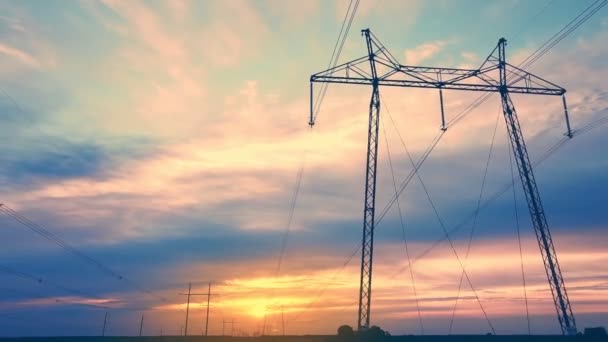 Высоковольтные линии электропередач на фоне заходящего солнца на открытой местности aerovideo. — стоковое видео