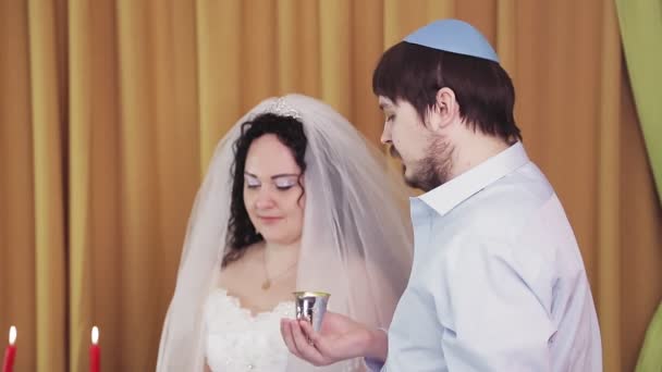 Durante la cerimonia di chuppah, gli sposi ebrei nella sinagoga bevono vino da un bicchiere d'argento.. — Video Stock