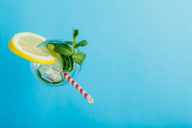 Limonlu ve naneli kokteyl salatalığı suyu mavi arka plan manzaralı bir peçetede..