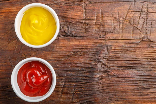 Sauce boats with cheese sauce and ketchup on a wooden table. Save a place. Horizontal photo
