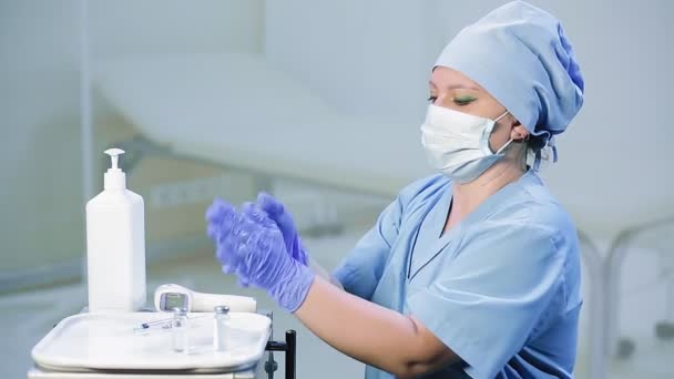 A woman doctor in a medical mask disinfects her gloved hands before the procedure — Stock Video