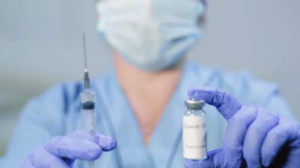 Vaccine and syringe in the hands of a woman doctors face out of focus in blur — Stock Video