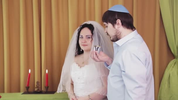 Podczas ceremonii chuppah, żydowska panna młoda i pan młody w synagodze piją wino ze srebrnej szklanki.. — Wideo stockowe