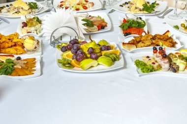 Salata aperatifleri ve meyveler açık büfe masasında beyaz masa örtüsüyle. Yatay fotoğraf