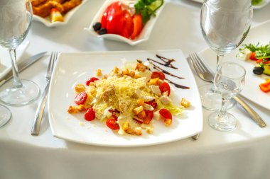 Beyaz masa örtüsü ve ziyafet masasında sezar salatası. Yatay fotoğraf