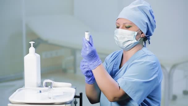 A female doctor in a medical mask is filling a syringe with a vaccine. — Stock Video