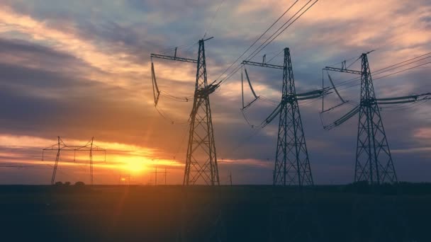 Líneas eléctricas de alto voltaje al atardecer contra el telón de fondo del sol poniente en un área abierta — Vídeos de Stock