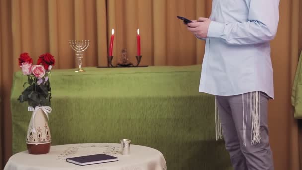 Avant la cérémonie du chuppah, un marié juif sans visage dans la salle de la synagogue compose un SMS par téléphone — Video