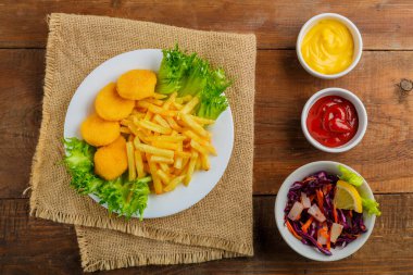 Tavuk nugget ile patates kızartması, Cole 'un yanında, ahşap bir masada peçetenin üzerinde yavaşça. Yatay fotoğraf