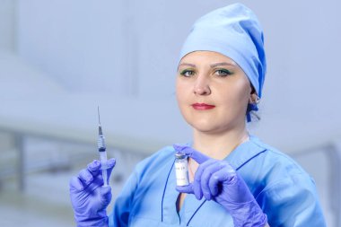 Tıbbi eldivenli bir doktor elinde aşı ve şırıngayla bir şişe tutuyor. Yatay fotoğraf